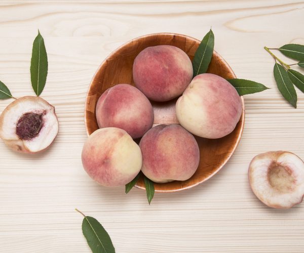 Fresh juicy peaches with leaves on a wooden table